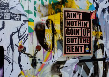 HACKNEY WICK, STRATFORD, LONDON, ENGLAND: 10/19/2015. Poster protesting about rent rises in London due to regeneration and gentrification of the area, on padlocked gate.