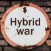 old rusty sign saying Hybrid War on a brick wall