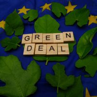 Some,Leaves,with,A,Wooden,Inscription,green,Deal,above,A,European,Flag.,Concept