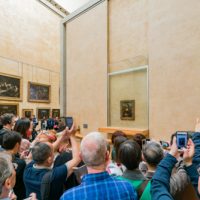 Tourist,Photographing,The,Famous,Mona,Lisa,Painting,In,The,Louvre
