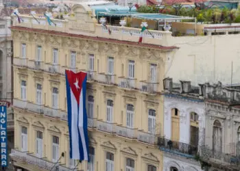 Havana, Cuba - Jan 01, 2020: Large Cuban flag hanging vertically on a facade of colonial building Inglaterra Hotel in the historical center of Old Havana. Space for copy.