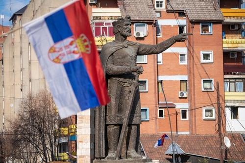 Serbian flag infront of Prince Lazar Hrebljanovic of Serbia statue monument in the Serbian northern part of the divided city of Kosovska Mitrovica. North Kosovska Mitrovica, Kosovo, Serbia 04.03.2022