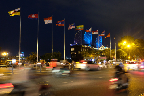 Ho Chi Minh, Vietnam - April 6, 2019: Multinational flags in ASEAN community country in the night time at Saigon with people, cars and motorcycles on the road.