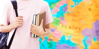 Student,Hand,With,Books,And,Map,,Learn,Languages