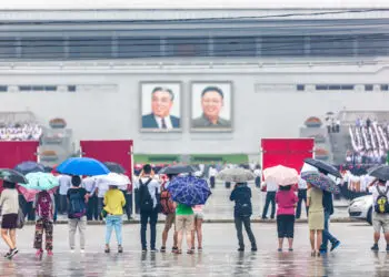 Pyongyang, North Korea - August 15th 2016 - Tourist observe a big group of students practicing an exercise in front of North Korea's leader pictures.