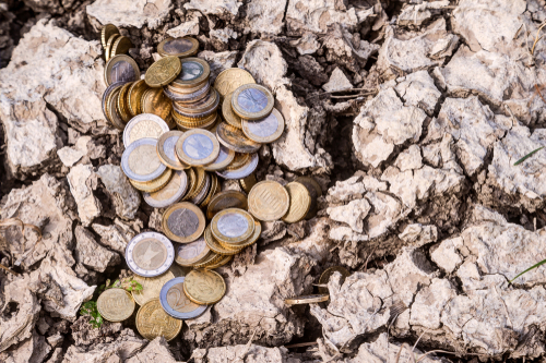 A heap of euro coins lie on the dry ground.