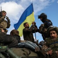 Ukrainian soldiers raise the national flag after reclaiming the city of Kupiansk