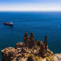 global oil shipping risks with oil tanker moving through narrow maritime route