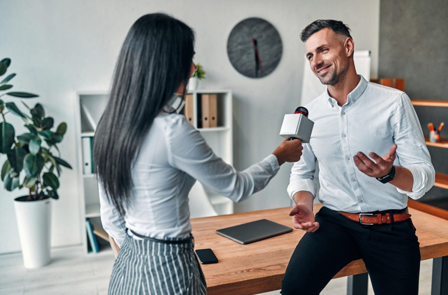 Professional journalist interviewing a company representative about media coverage benefits and business reputation