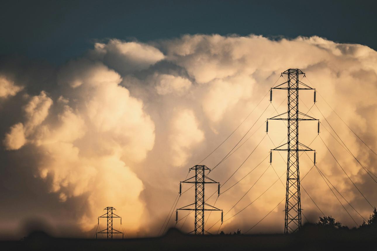 Ukraine energy crisis illustrated by high-voltage electricity transmission towers beneath a cloudy sky.