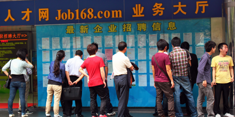 GUANGZHOU, CHINA, MARCH 20, 2012: People looking for jobs browse vacations on street board. Street advertisements and job boards are popular places for unemployed.