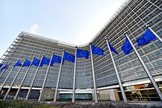 EU Russia sanctions talks in Brussels as EU and Ukrainian flags fly outside the Berlaymont
