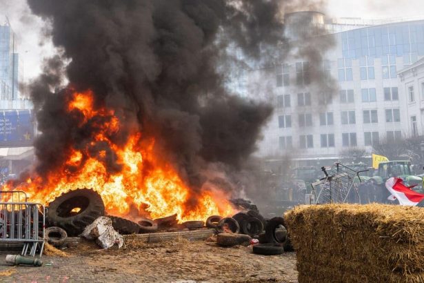 Brussels police clashes coverage illustrated by smoke rising during an earlier protest outside the European Parliament.