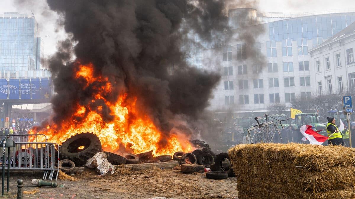 Brussels police clashes coverage illustrated by smoke rising during an earlier protest outside the European Parliament.