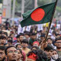 Bangladeshi demonstrators holding signs and banners during a protest, showing grassroots participation in the unrest