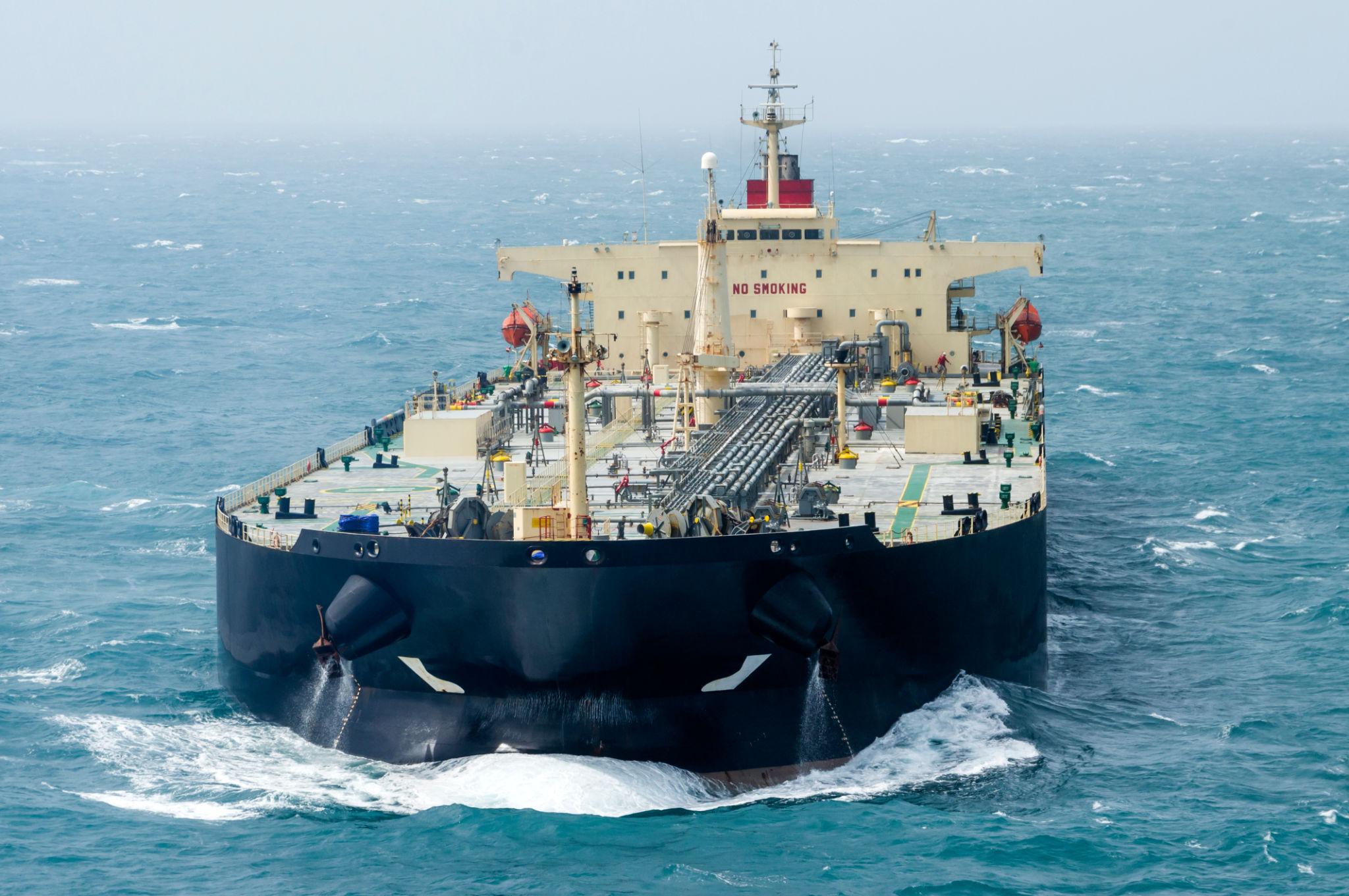 global oil shipping risks shown through cargo vessel navigating open sea under tense conditions