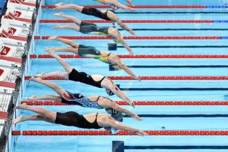 Professional swimmers diving into pool at International Swimming League event
