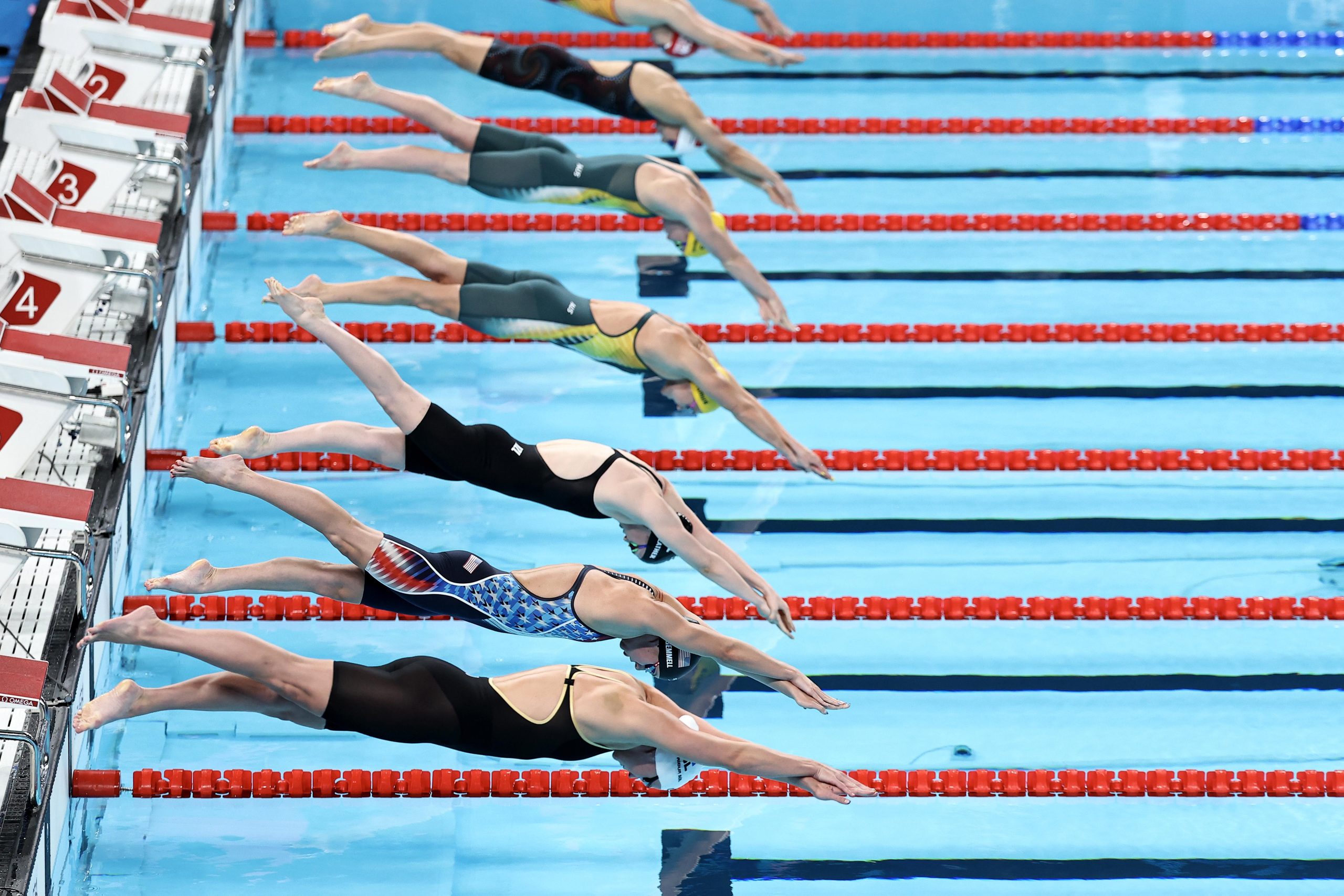 Professional swimmers diving into pool at International Swimming League event