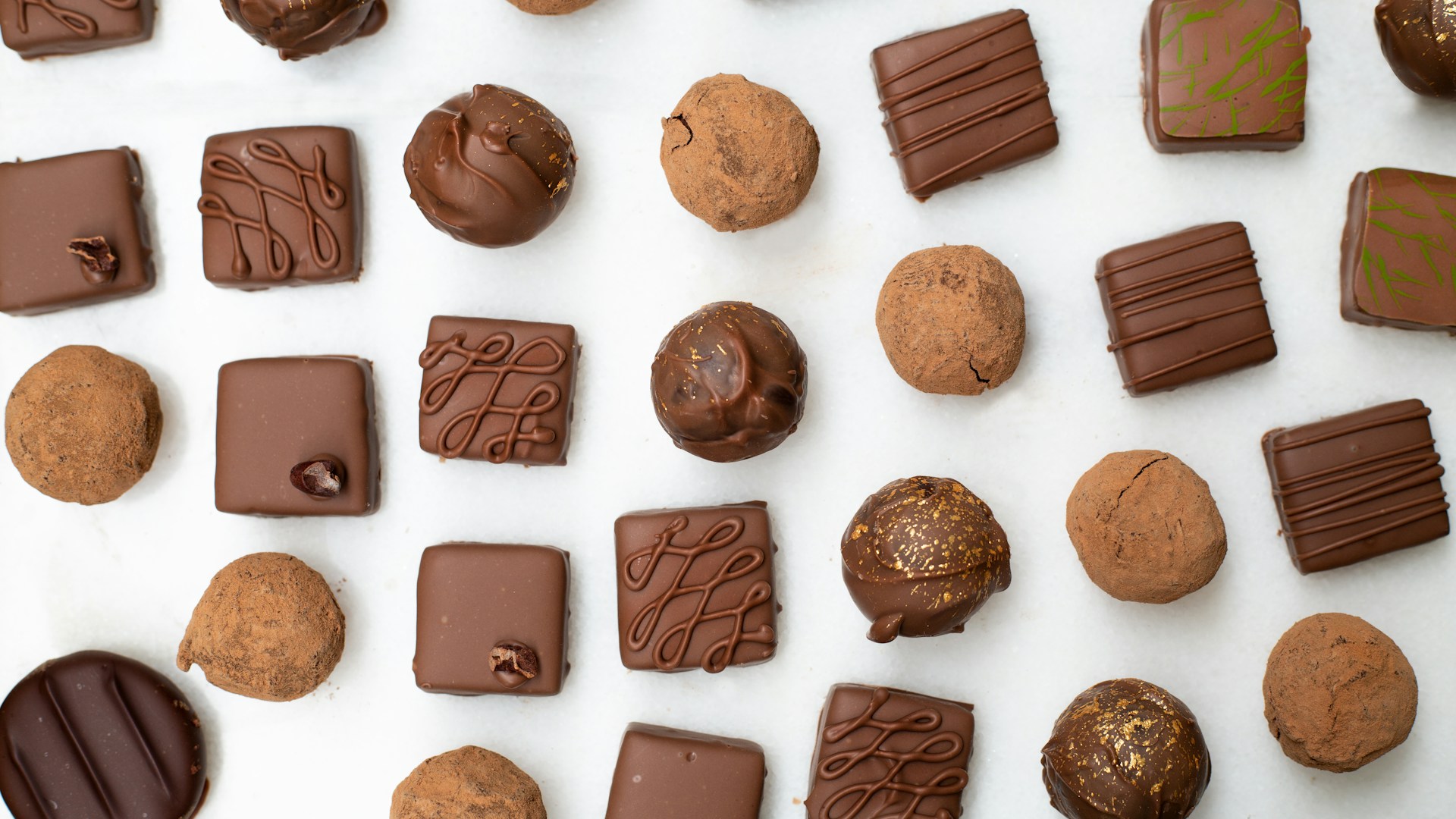Artisan chocolatier preparing Belgian pralines by hand, illustrating the craft behind Leonidas chocolates.