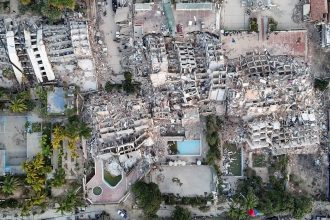 Teen Venezuela quake survivor standing near earthquake-damaged buildings in Venezuela