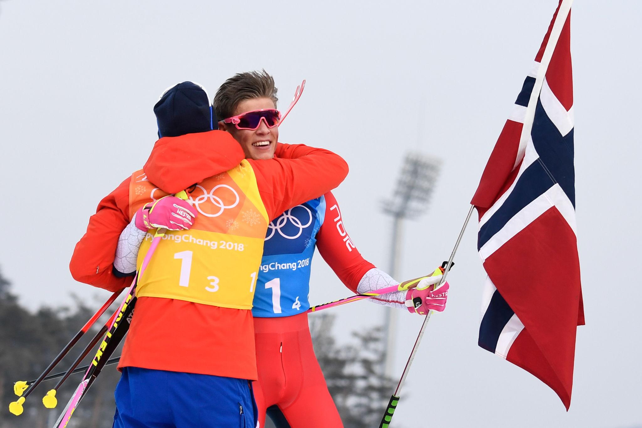 Johannes Klaebo gold medal podium moment with Norway flag Milan 2026